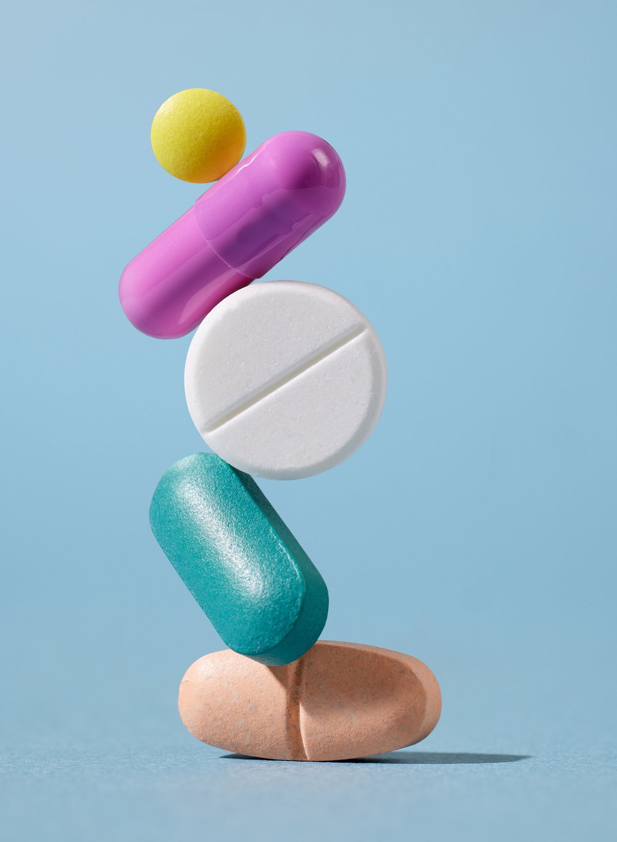 Tower of various colorful pills on blue background