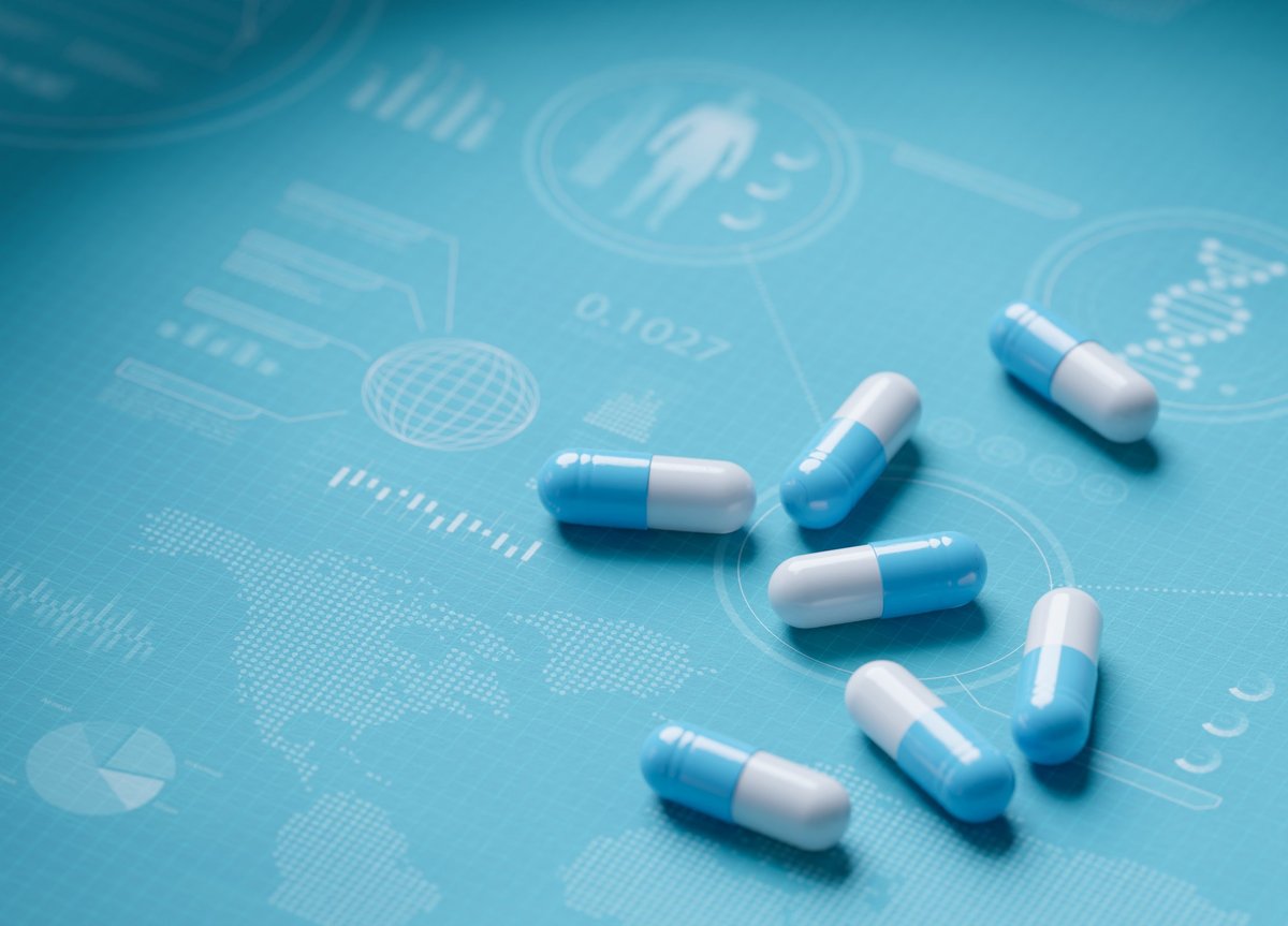 Blue and white medical capsules on flat surface with pharmaceutical charts