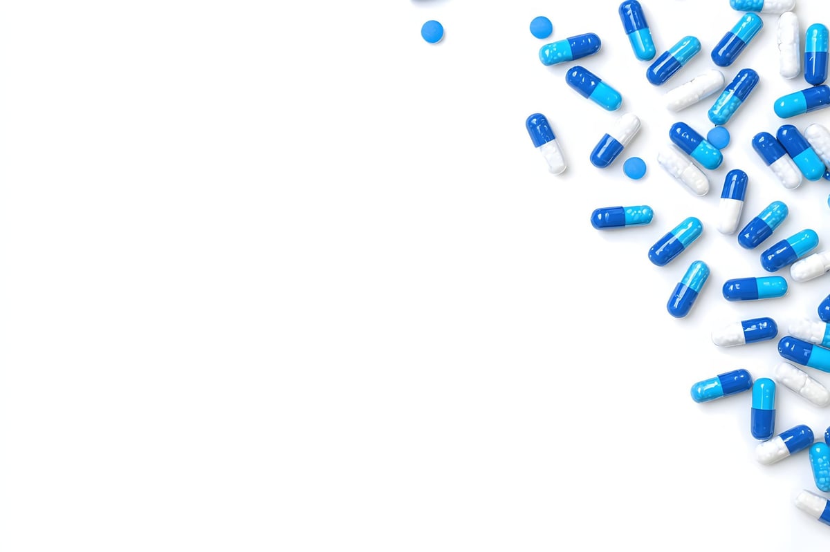 Scattered arrangement of blue and white capsules on a white background