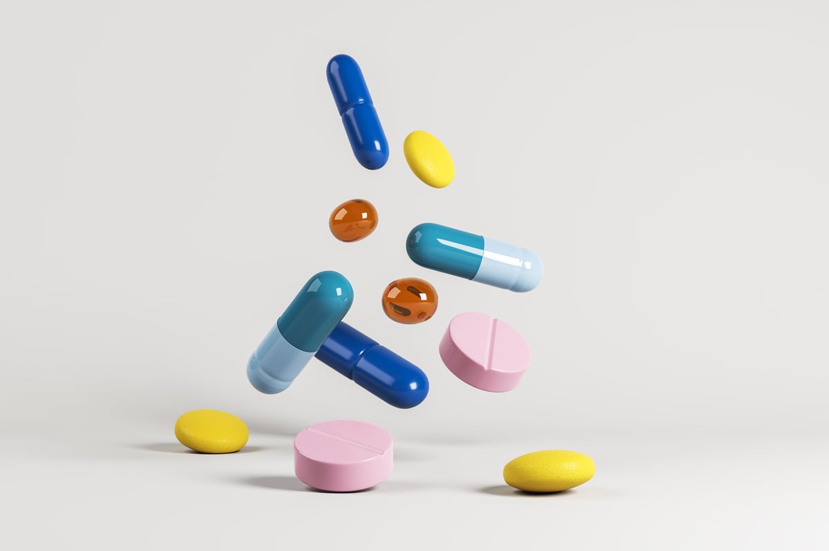 Floating colorful capsules and tablets in light abstract background